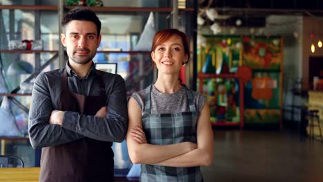 Portrait-of-two-proud-small-business-owners-standing-inside-new-spacious-cafe-and-smiling.-Successful-business-start-up,-happy-people-and-food-service-concept.