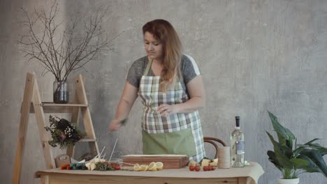 Woman-pinning-slices-of-assorted-cheese-on-skewers