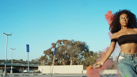 Young-woman-dancing-outside-with-smoke-grenade-at-sunset-on-rooftop-parking-garage