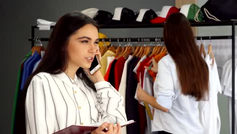 Beautiful-female-shop-assistant-talking-on-the-phone,-working-at-the-clothing-store