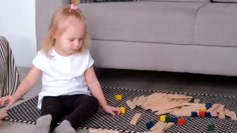 Kleine-charmante-blonde-Mädchen-spielen-Holzblöcke,-die-neben-dem-Sofa-zu-sitzen.