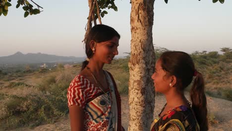 Two-girlfriends-talk-on-the-mobile-phone-happy-call-exchange-phone-park-deserted-hill-top-lover-joy-share-love-bond-together-summer-hot-day-teamwork-handheld-stabilized-two-shot-medium-close-up-look