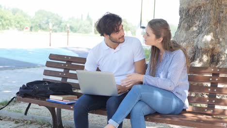 einige-junge-Studenten-Mann-und-Frau-gemeinsam-mit-Laptop-Computer-in-einer-Straße-im-Freien-im-Sommer