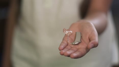 Little-girl-shows-a-hearing-aid-on-a-palm