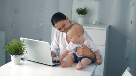 Young-mother-working-with-laptop-at-home