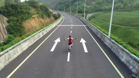 Vista-aérea-de-mujer-experimentada-manos-libre-ciclismo-montar-bicicleta-en-carretera