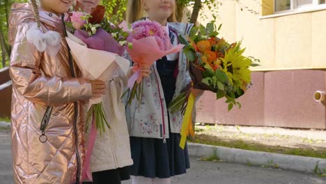 Adorable-female-schoolchildren-with-flowers,-crane-shot