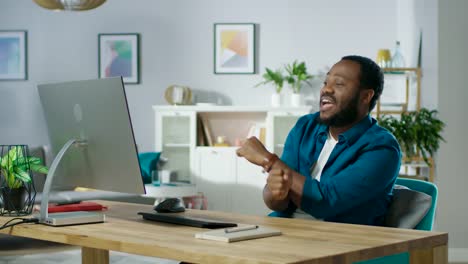 Portrait-of-the-Handsome-African-American-Man-Dancing-while-Sitting-at-His-Workplace.-Young-Man-Having-Fun-at-Home.-In-Slow-Motion.