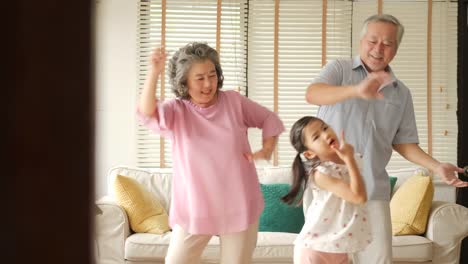 Happy-asian-senior-couple-dancing-together-with-their-granddaughters-at-home.-Senior-lifestyle-family-concept.