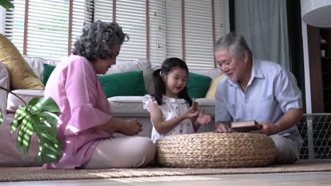 Couple-senior-and-kids-girl-playing-puzzle-games-together-in-living-room-at-home.-Concept-of-caucasian-family,-education,-growing-learn-and-development-of-age.-4k-resolution.