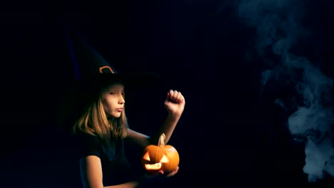 Girl-wearing-black-witch-hat-holding-jack-o'-lanterns