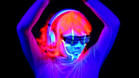 Woman-with-UV-cyborg-face-paint,-wig,-glowing-glasses,-clothing-dancing-and-listening-to-music-with-headphones.-Asian-woman.-.