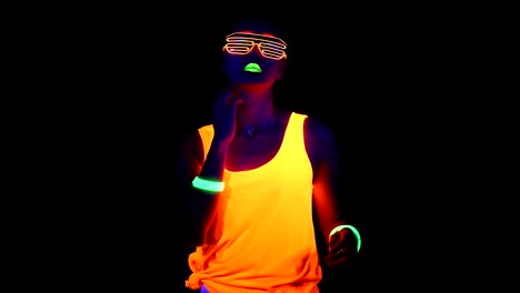 Woman-with-UV-face-paint,-glowing-clothing,-glowing-glasses,-bracelet-dancing-in-front-of-camera,-half-body-shot.-Asian-woman.-.