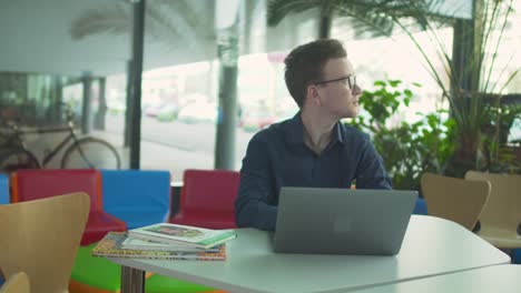 Junger-Mann-arbeitet-mit-Laptop-in-der-Bibliothek