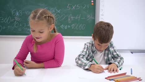 private-school,-children-draw-color-markers-on-white-paper-while-sitting-at-desk-in-the-classroom