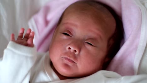 Neugeborenes-Babymädchen-im-Kinderbett-liegend-wacht-auf-und-erstreckt-sich