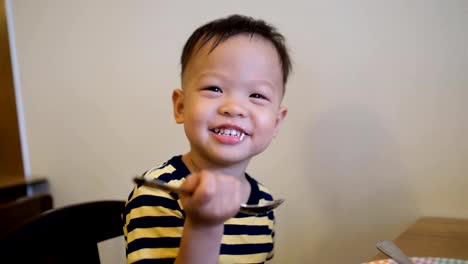 Toddler-boy-use-spoon-eating-food-by-himself