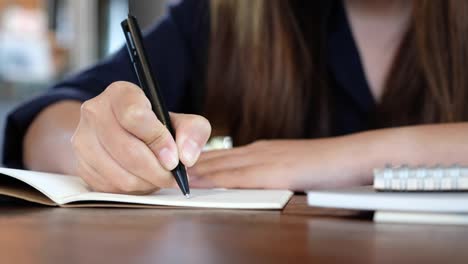 Eine-Frau-auf-einem-weißen-leeren-Notebook-auf-Tabelle-aufschreiben