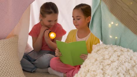 happy-girls-reading-book-in-kids-tent-at-home