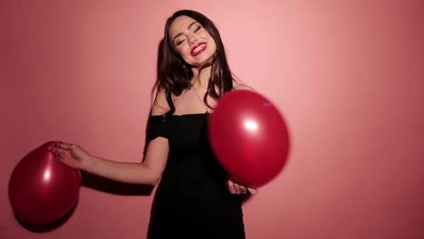 Brunette-happy-woman-dance-with-balloons-and-confetti-in-pink-background-wear-red-dress