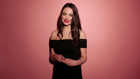 Brunette-happy-woman-laughing-with-confetti-in-pink-background-wear-red-dress