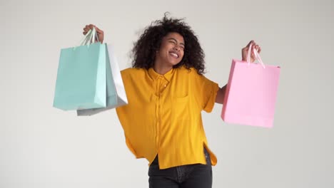 African-american-mujer-sosteniendo-bolsas-de-compras-y-bailar