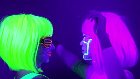 Langsame-Motin-von-schönen-sexy-Frauen-mit-fluoreszierenden-Make-up-und-Kleidung-Tanz-im-Neonlicht.-Night-Club,-Party-Konzept.