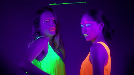 Langsame-Motin-von-schönen-sexy-Frauen-mit-fluoreszierenden-Make-up-und-Kleidung-Tanz-im-Neonlicht.-Night-Club,-Party-Konzept.