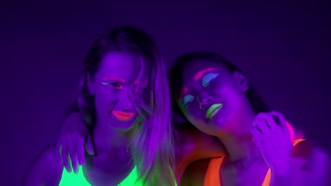 Langsame-Motin-von-schönen-sexy-Frauen-mit-fluoreszierenden-Make-up-und-Kleidung-Tanz-im-Neonlicht.-Night-Club,-Party-Konzept.