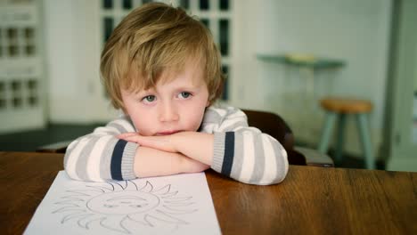 Sad-Looking-Young-Boy-Leaning-On-Table