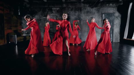 siete-mujeres-encantadoras-de-bailarines-están-bailando-en-la-sala-de-ensayo,-llevando-vestidos-de-rojo,-en-suelo