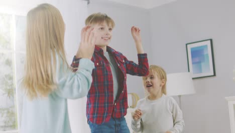 Zwei-niedliche-kleine-Mädchen-und-junge,-bezaubernde-haben-Spaß,-springen-hoch-auf-einer-Couch-zu-Hause.-Happy-Kids-tanzen-auf-einem-Sofa-im-sonnigen-Wohnzimmer.-In-Zeitlupe.