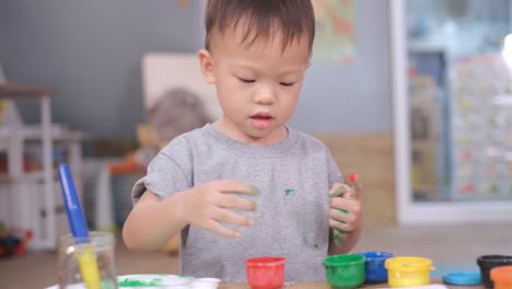 Asian-2--3-years-old-toddler-baby-boy-child-finger-painting-with-hands-and-watercolors