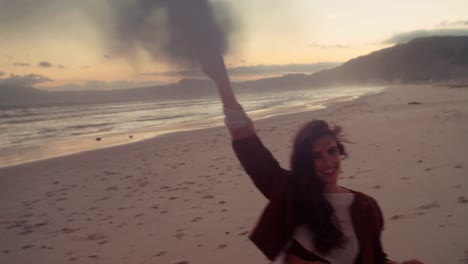 Attractive-Boho-Hipster-Girl-walking-on-Beach-with-smoke-flare