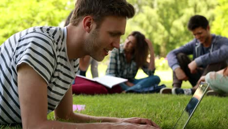 Student-mit-laptop-und-Klassenkameraden-hinter-ihm-reden