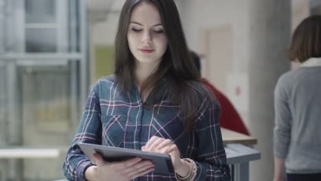 Chica-joven-hermosa-morena-estudiante-está-utilizando-un-equipo-tablet-PC-en-una-Universidad.