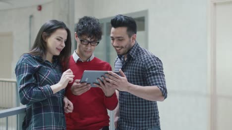 Gruppe-von-jungen-multi-ethnischen-Studenten-nutzen-ein-Tablet-Computers-in-einer-Universität.