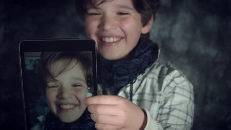 4K-tiro-alta-tecnología-de-un-niño-haciendo-un-Selfie-en-su-Tablet-y-ríe