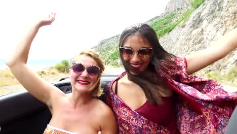 Two-happy-girls-partying-while-riding-in-cabriolet