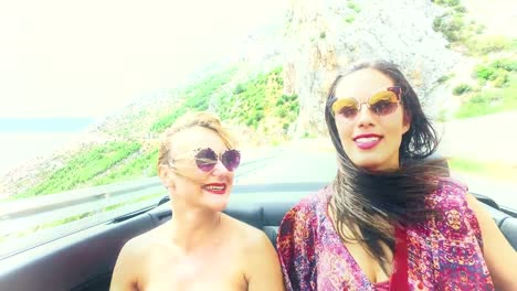 Two-happy-girls-partying-while-riding-in-cabriolet,-graded-with-yellow-filter