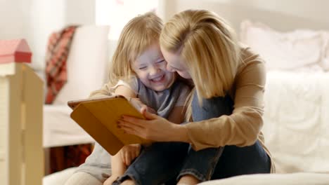 Beautiful-Mother-and-Her-Little-Daughter-Have-Good-Time-Reading-Children's-Books-on-a-Tablet-Computer.