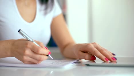 Mano-femenina-con-pluma-de-escribir-en-el-cuaderno