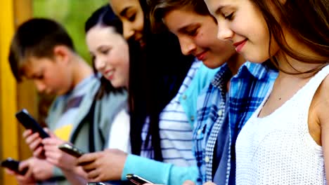 Group-of-school-friends-using-mobile-phone-outside-school