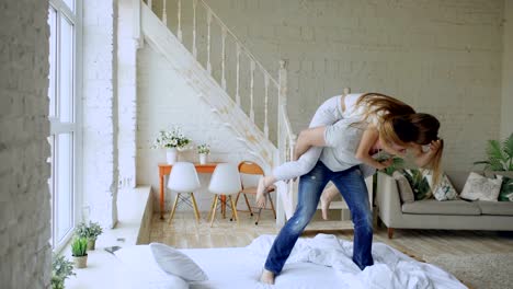 Young-beautiful-and-loving-couple-dancing-and-kissingwhile-having-piggyback-ride-on-bed-in-the-morning-at-home