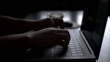 man-at-the-table-is-working-in-the-evening-on-a-laptop-by-the-window