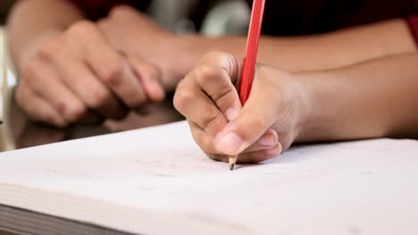 Primer-plano-de-niña-mano-lápiz-de-escritura-en-libro-de-ejercicios