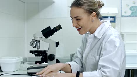 Mujer-sorprendida-trabajando-con-un-microscopio-en-el-laboratorio