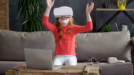 Little-girl-is-sitting-on-the-sofa-in-the-room-in-vr-headset-and-dong-something-with-the-hands