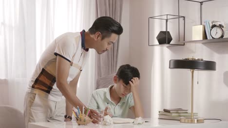 Asian-father-walking-into-reading-room-talking-to-son-frustrated-with-homework