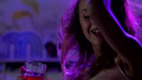 close-up-happy-girl-dance-at-night-club-with-glass-cocktail,-beautiful-woman-with-beverage-on-party-in-blue-lights